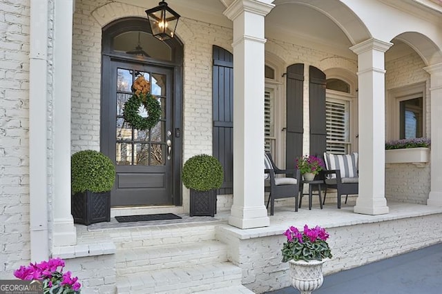 property entrance featuring covered porch and brick siding