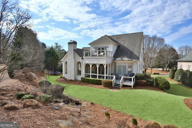 back of house with a trampoline, a chimney, a lawn, and a balcony