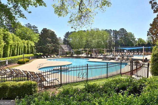 pool featuring a patio area, fence, and an outdoor structure