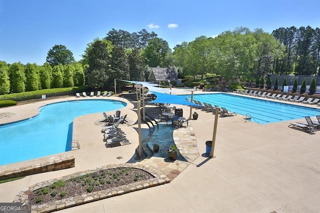 community pool featuring a water slide and a patio area