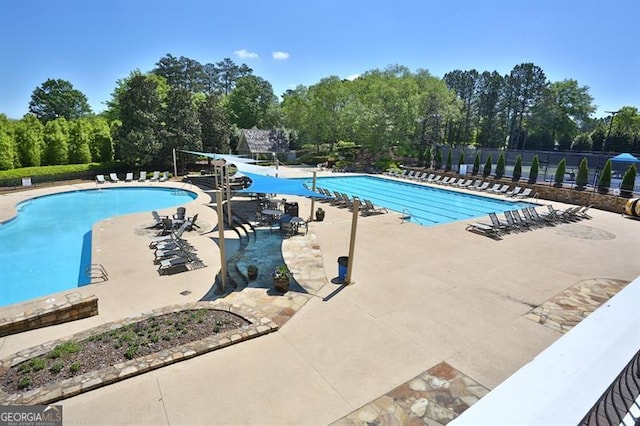 pool featuring fence, a water slide, and a patio