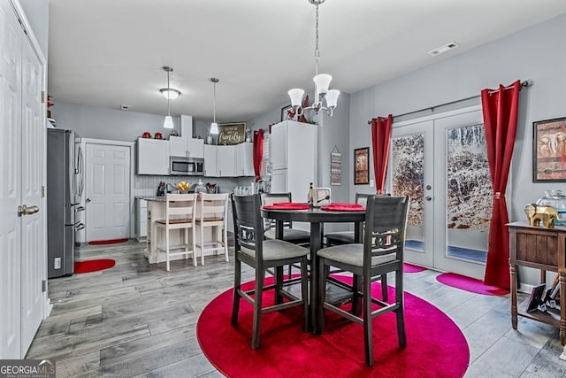 dining space with french doors, an inviting chandelier, visible vents, and light wood-style floors