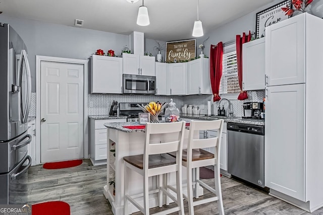 kitchen with light wood-type flooring, tasteful backsplash, white cabinetry, and stainless steel appliances