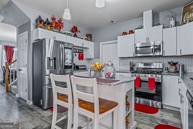 kitchen with appliances with stainless steel finishes, light stone counters, and white cabinetry