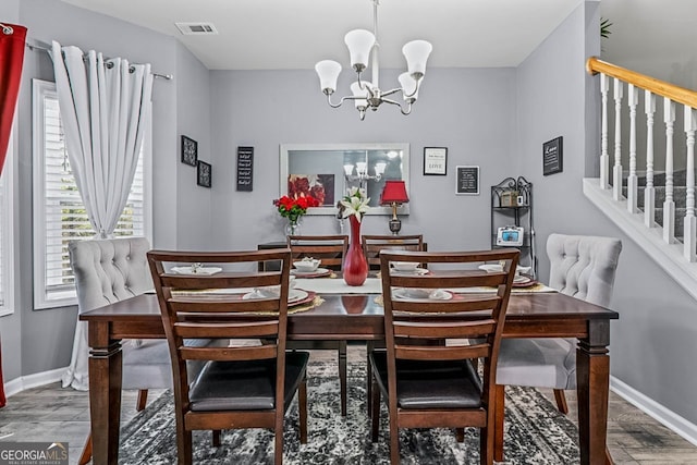 dining area with stairs, wood finished floors, visible vents, and a notable chandelier