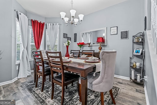 dining space with baseboards, an inviting chandelier, and wood finished floors