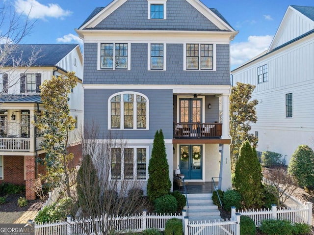 view of front of house with a fenced front yard, french doors, and a balcony