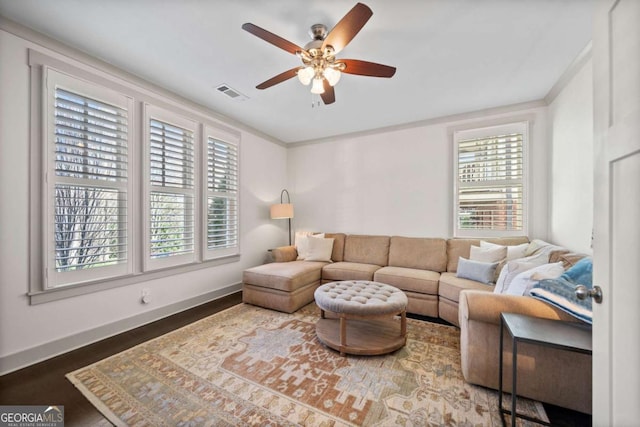 living room featuring a wealth of natural light, a ceiling fan, visible vents, and baseboards