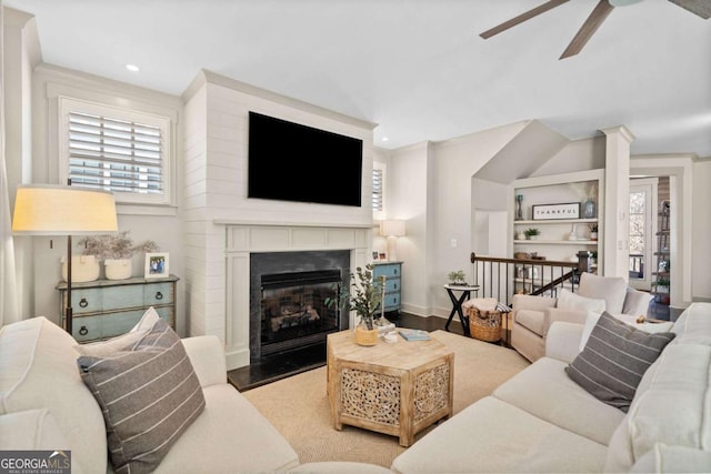 living area featuring a ceiling fan, plenty of natural light, a fireplace, and wood finished floors