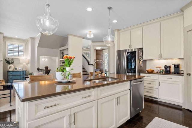 kitchen featuring appliances with stainless steel finishes, dark countertops, a sink, and tasteful backsplash