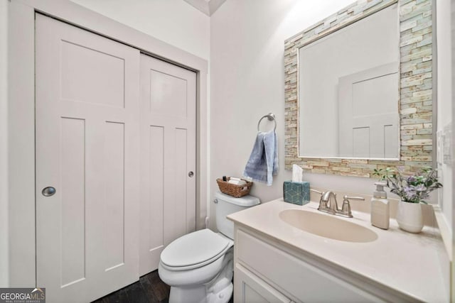 bathroom featuring toilet, wood finished floors, and vanity