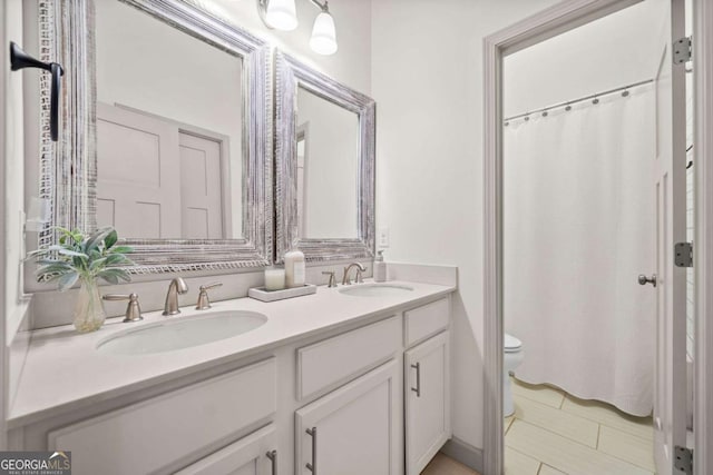 full bath with double vanity, a sink, toilet, and a shower with curtain