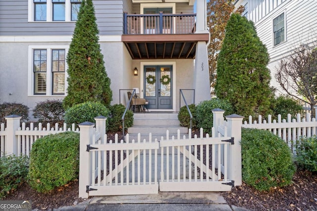 entrance to property with stucco siding, a gate, fence, and french doors