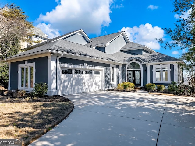 view of front of property with french doors, stucco siding, an attached garage, and concrete driveway