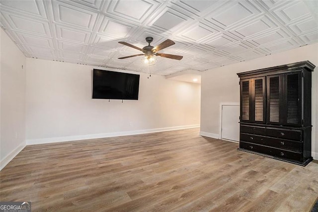 below grade area featuring an ornate ceiling, ceiling fan, baseboards, and wood finished floors