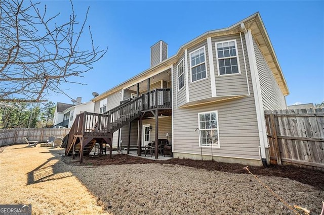 rear view of house with a patio, a fenced backyard, stairway, a wooden deck, and a chimney