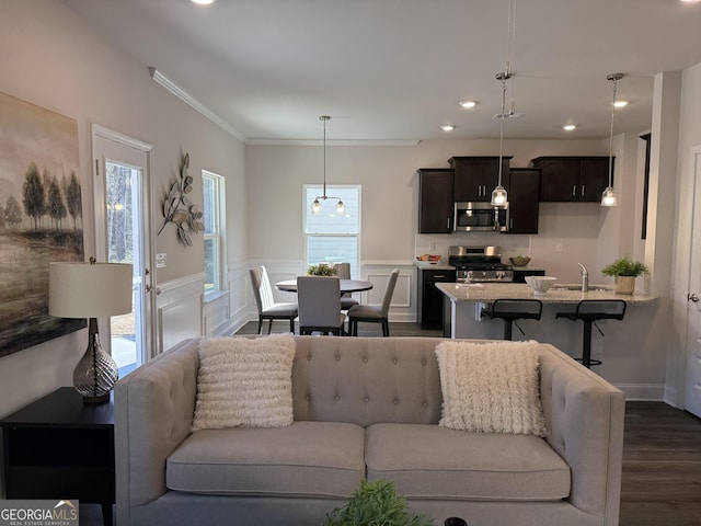 living area with crown molding, wainscoting, dark wood finished floors, and a decorative wall