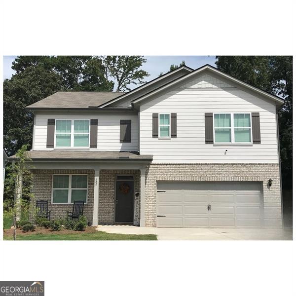 traditional home with a porch, an attached garage, brick siding, and driveway