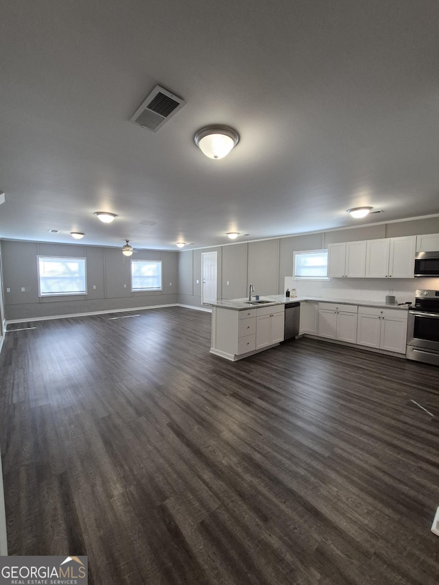 kitchen featuring visible vents, appliances with stainless steel finishes, open floor plan, white cabinets, and a peninsula