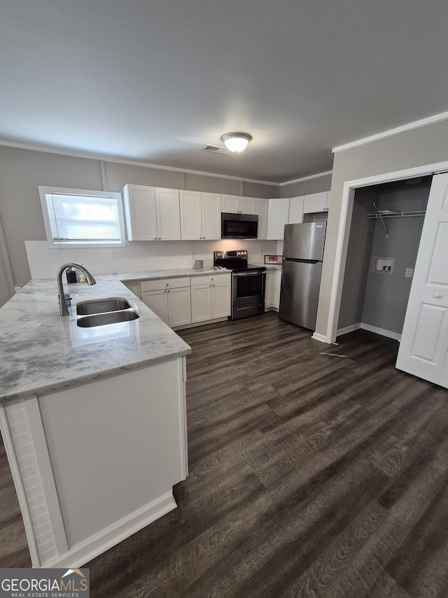 kitchen featuring appliances with stainless steel finishes, dark wood-type flooring, light stone countertops, white cabinetry, and a sink