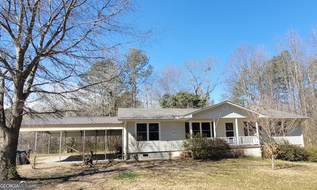 view of front facade with dirt driveway, a chimney, covered porch, a front lawn, and a detached carport