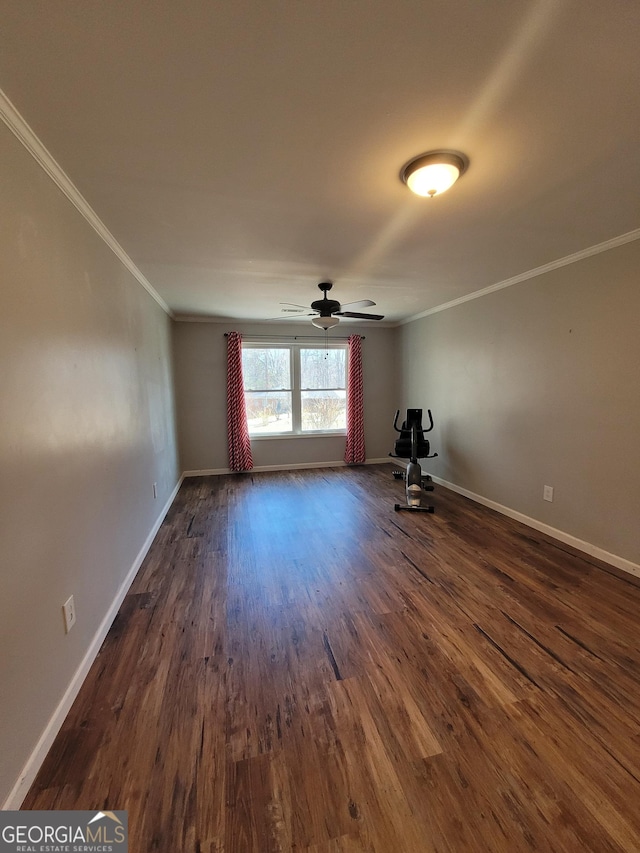 empty room featuring dark wood-style floors, ornamental molding, baseboards, and ceiling fan