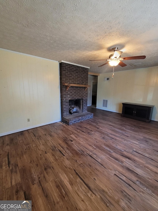 unfurnished living room featuring a ceiling fan, a fireplace, visible vents, and wood finished floors