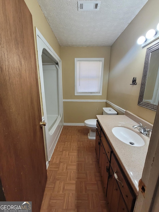 bathroom with baseboards, visible vents, toilet, a textured ceiling, and vanity