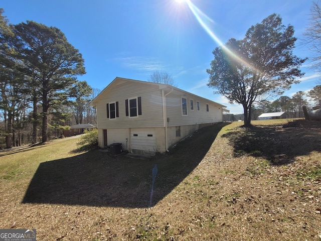 view of side of property featuring a garage, central AC, a lawn, and driveway