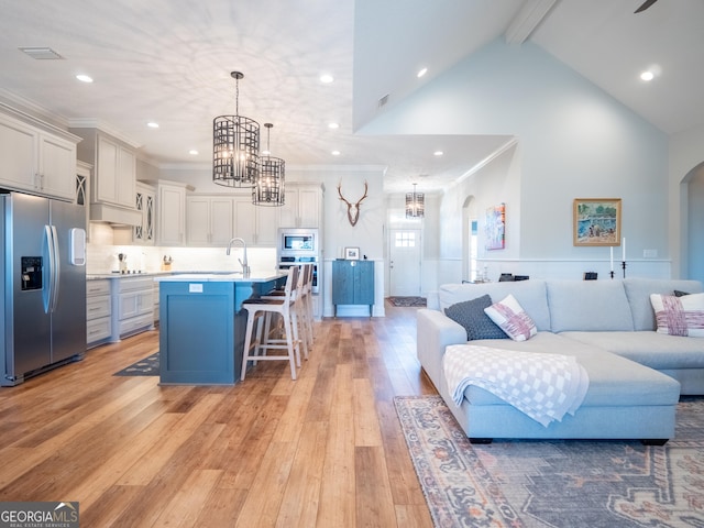 kitchen with arched walkways, a breakfast bar area, open floor plan, light countertops, and stainless steel appliances