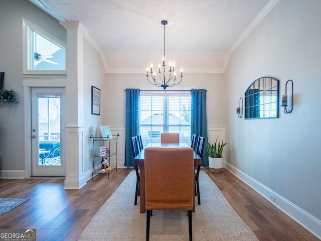 dining room featuring plenty of natural light, crown molding, a notable chandelier, and wood finished floors