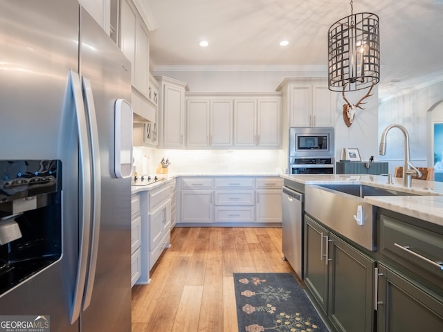 kitchen featuring decorative light fixtures, appliances with stainless steel finishes, ornamental molding, white cabinets, and light wood-type flooring