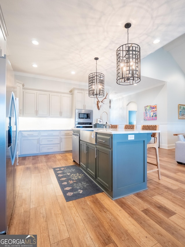 kitchen featuring stainless steel appliances, light countertops, light wood-style floors, pendant lighting, and a notable chandelier