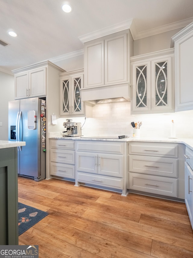 kitchen with light wood-style floors, ornamental molding, backsplash, and stainless steel fridge with ice dispenser