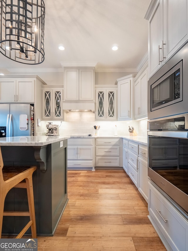 kitchen with light wood-style floors, tasteful backsplash, appliances with stainless steel finishes, and crown molding