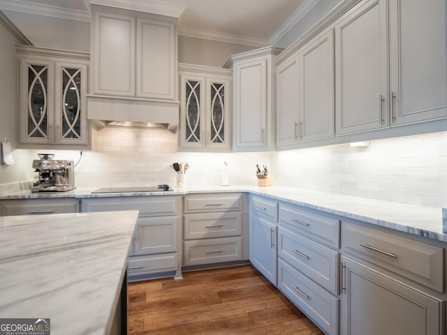 kitchen with dark wood-style flooring, backsplash, ornamental molding, ventilation hood, and black electric cooktop