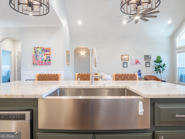 kitchen featuring arched walkways, a sink, open floor plan, light stone countertops, and dishwasher