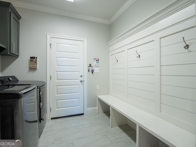 laundry room featuring washing machine and dryer, cabinet space, and crown molding