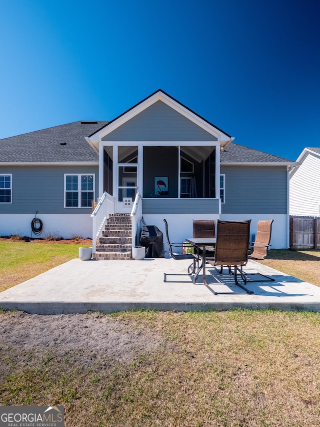 back of house featuring a patio, a yard, roof with shingles, and a sunroom