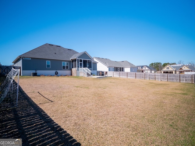 back of house featuring a residential view, a sunroom, a fenced backyard, and a yard