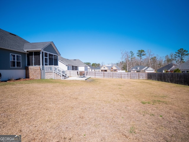 view of yard with a sunroom, a fenced backyard, and a patio