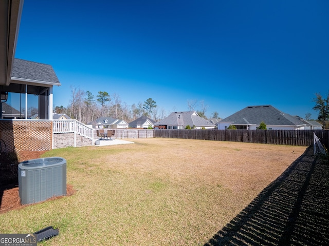 view of yard featuring central AC, a patio area, fence, and a residential view