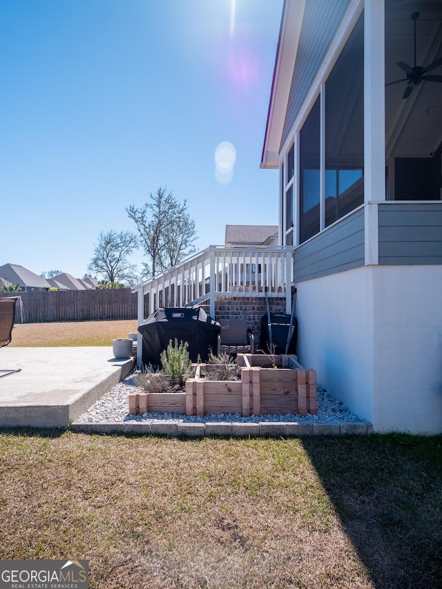 view of yard with fence, a garden, a sunroom, a wooden deck, and a patio area