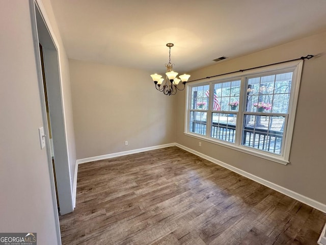 unfurnished dining area with a notable chandelier, baseboards, visible vents, and dark wood-style flooring