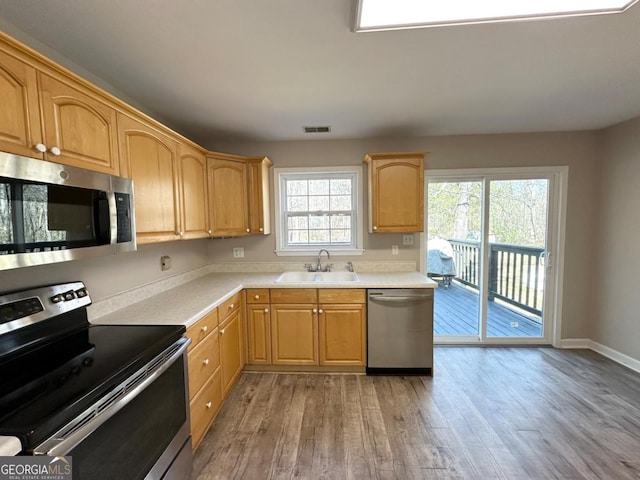 kitchen with visible vents, appliances with stainless steel finishes, light wood-style flooring, and a sink