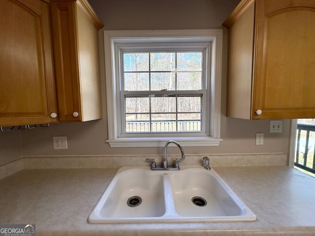 kitchen featuring a healthy amount of sunlight, brown cabinetry, light countertops, and a sink