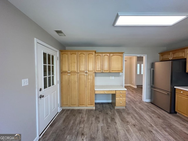 kitchen with light countertops, dark wood-style flooring, built in study area, and freestanding refrigerator