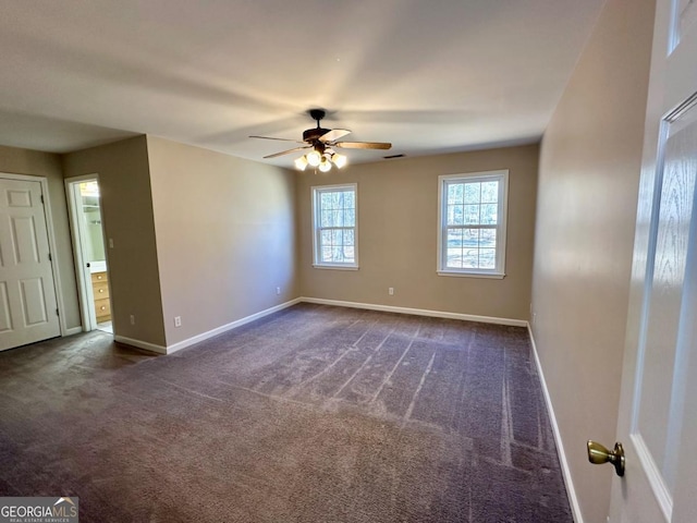 spare room featuring baseboards, visible vents, dark carpet, and ceiling fan