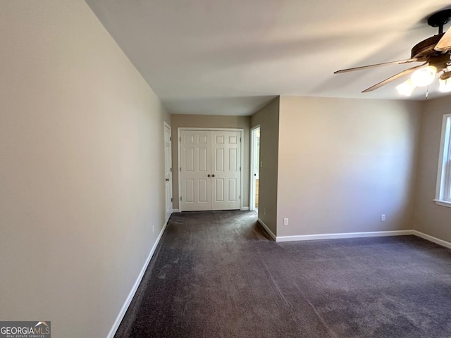 spare room featuring ceiling fan, baseboards, and dark colored carpet