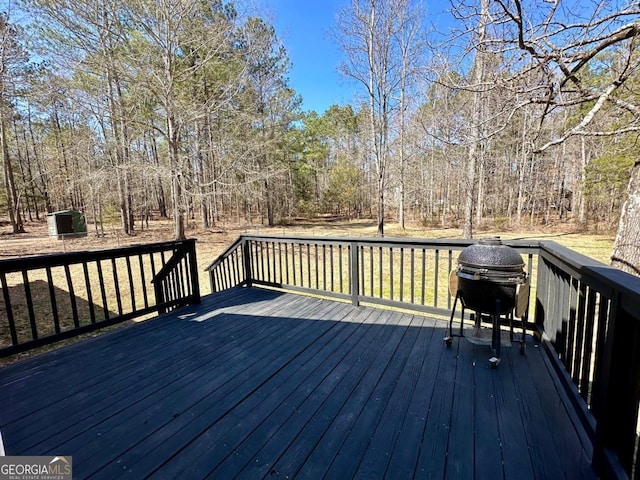 wooden deck with a view of trees and area for grilling